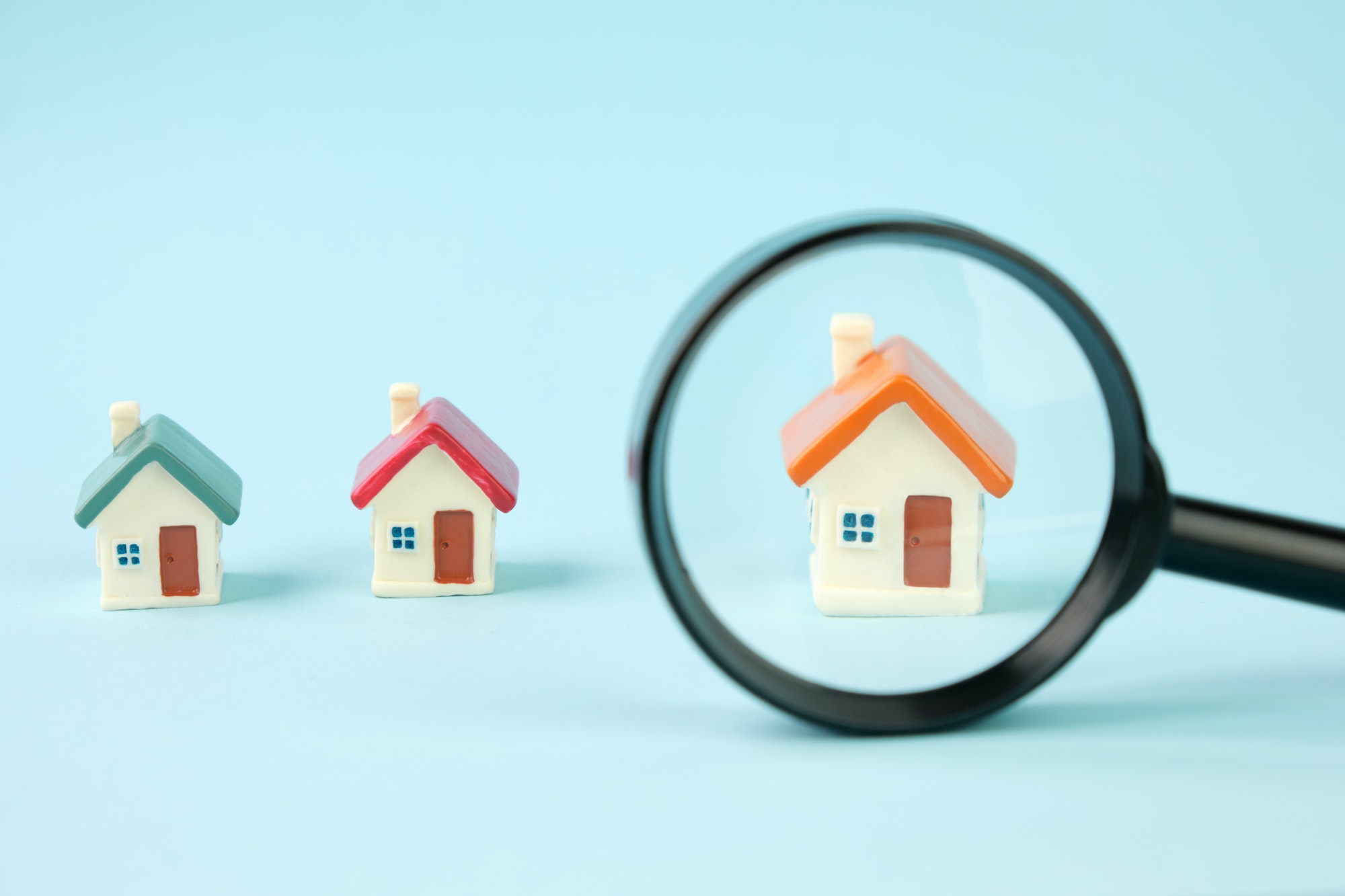 Small houses under a magnifying glass. Real estate search concept, purchase and sale of housing